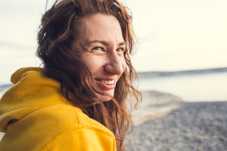 Portrait of a long haired girl. Smiling brunette. Woman without makeup. Long curly hair. A woman is...