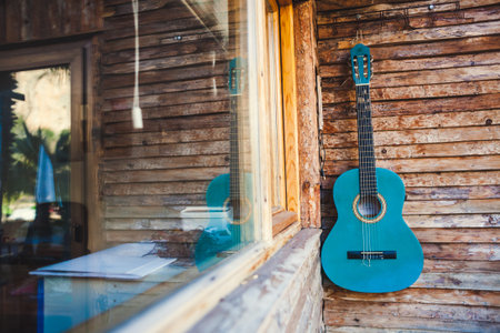 Geyikbayiri, Antalya, Turkey. March 4, 2019. Blue acoustic guitar hanging on a wooden wall.