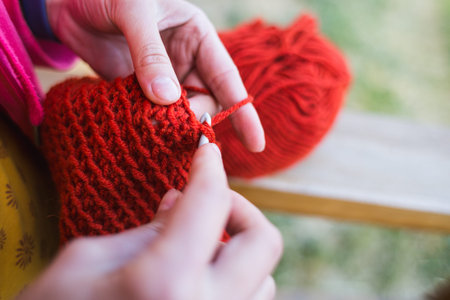 Woman crochets. Female hands close-up. The girl is engaged in needlework. A ball of red thread and a...