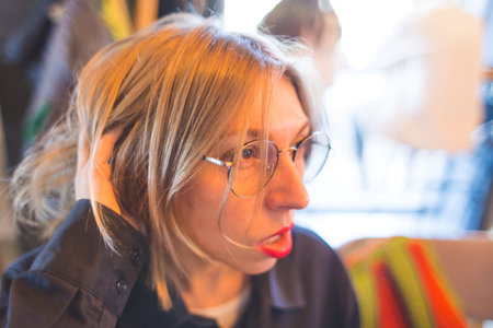Portrait of a blonde in glasses. The smiling girl. Lips with red lipstick. A woman is sitting in a...