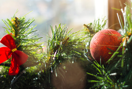 Decorated Christmas tree branch. Celebrating the winter holidays. Window decoration with spruce...