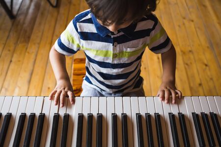 A child learns to play the piano. The boy makes keys. Music studio. Children's fingers on the black and white keys.の写真素材