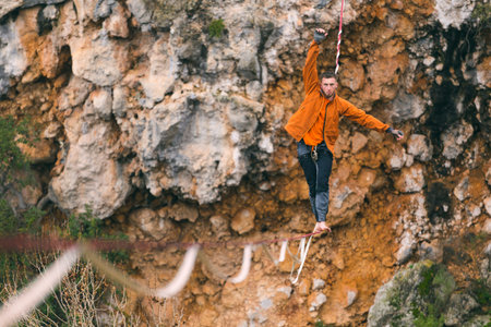 A man is walking along a stretched sling. Highline in the mountains. Man catches balance....