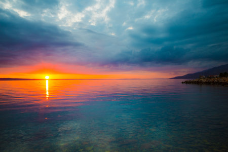 Sea coast of Croatia. Sea and sky with clouds. Calm water. Evening and sunset sun.