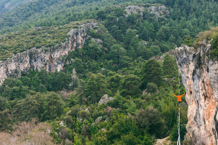 A man is walking along a stretched sling. Highline in the mountains. Man catches balance....