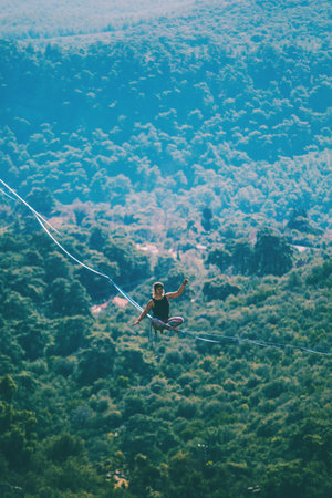 Highline on the background of the mountains. A woman sits on a stretched sling. Performance of a...
