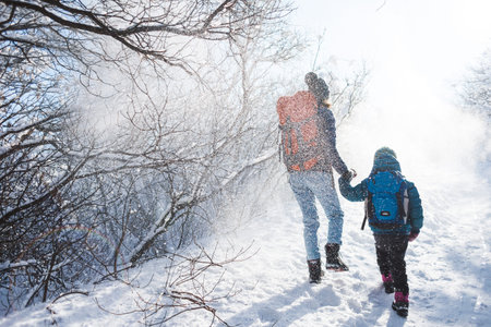 Woman with a child on a winter hike in the mountains. The boy travels with mother in the cold...