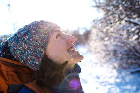 Portrait of a girl in a knitted hat. Smiling woman with a backpack on a background of a snowy...