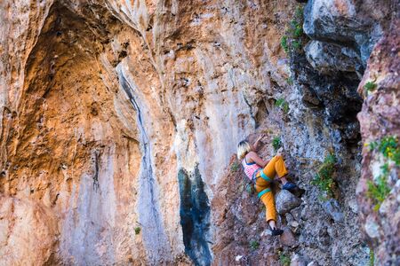 A girl climbs a rock. The athlete trains in nature. Woman overcomes difficult climbing route. Strong climber. Extreme hobby. Rock climbing in Turkey.の写真素材
