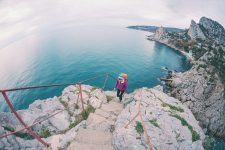 A woman climbs the stairs to the top of the mountain. A girl with a backpack climbs. Ladder on the...