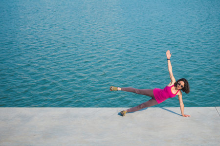 Woman warming up before jogging. The girl is stretched on the city promenade. Training in the city....