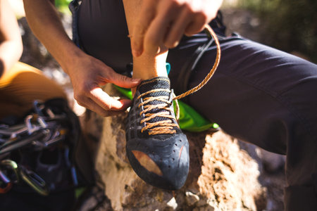 Rock climber puts on climbing shoes and ties shoelaces. A girl sits on a stone and puts on climbing...