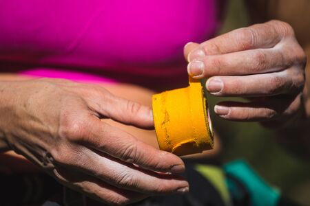 Rock climber bandages his fingers with a bandage, Hand protection from damage, yellow protection tape, Preparing to overcome the climbing route, Female hands close-up.の写真素材