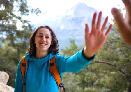 A woman with a backpack gives five to a friend, Traveler on a background of mountains, Travel to the picturesque places of Turkey, Gesture of greeting.の写真素材