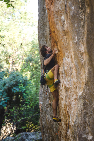 A strong man overcomes a difficult climbing route on a natural terrain. Rock climber trains on the...