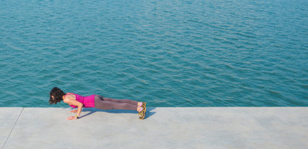 The woman is pushing up. Woman warming up before jogging. Girl is stretched on the city promenade....