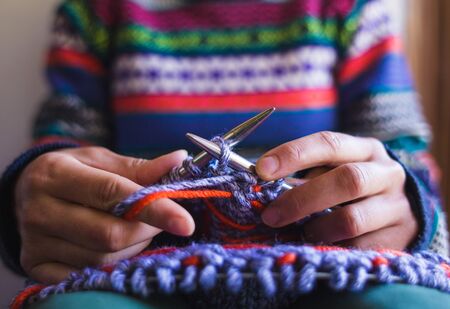 Woman knits a hat from woolen yarn. Female hands close-up. Handmade. Colored yarn and knitting needles.の写真素材