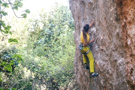 A girl climbs a rock on the background of the forest, The athlete trains in nature, Woman overcomes difficult climbing route, Strong climber, Extreme hobby, Rock climbing in Turkey.の写真素材