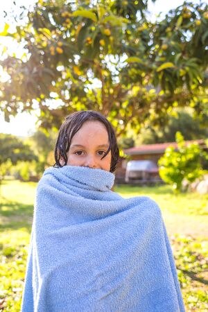 The child wipes with a towel after swimming in the pool. Wet boy wipes with a towel.の写真素材