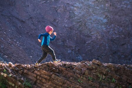 A boy runs along a mountain path. A child walks through the forest. Active kid walks in the park.の写真素材