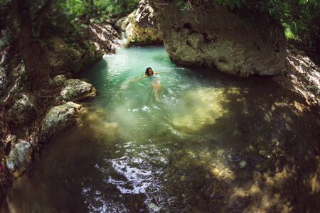 A woman in a swimsuit swims in a mountain river, The girl goes into cold water, Picturesque place of Turkey.の写真素材