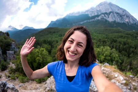 A woman takes a selfie on top of a mountain, a girl is photographed against a background of a mountain valley, a trip to the picturesque places of Turkey.の写真素材