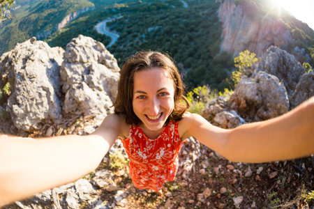 A woman takes a selfie on top of a mountain, a girl is photographed against a background of a mountain valley, a trip to the picturesque places of Turkey.の写真素材