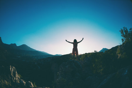 A girl in a dress stands on top of a mountain, a woman looks at a mountain valley, traveling around Turkey, The girl travels to beautiful places, Reaching the goal, Beautiful landscape.の写真素材