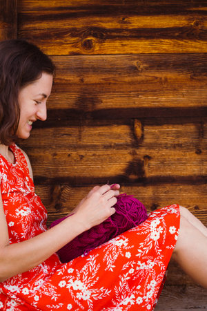 Woman knits sitting on the veranda of a wooden house, Needlework during quarantine, The girl knits...