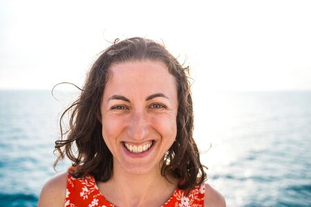 Portrait of a smiling woman on a background of the sea, a girl resting on the sea coast, emotional brunette.の写真素材