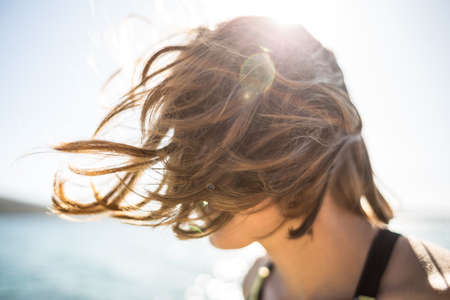 Portrait of a smiling girl with freckles. Hair blows in the wind. Holidays on the coast.の写真素材