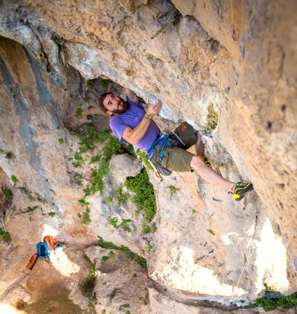 A strong man climbs a cliff, Climber overcomes a difficult climbing route on a natural terrain, Rock...