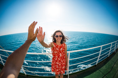 A woman is sailing on a cruise ship, a girl is standing near the fence on a ship and looking at the...