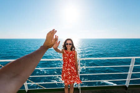 A woman is sailing on a cruise ship, a girl is standing near the fence on a ship and looking at the sea, traveling by ferry, a brunette in a summer dress admires the ocean.の写真素材
