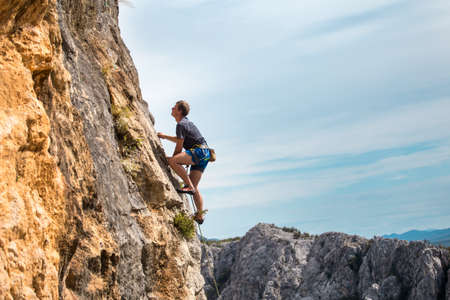 Rock climber on the background of mountains and sea. A man climbs on a rock. Training in nature. Active lifestyle. Extreme hobby. Strength and endurance in sports.の写真素材
