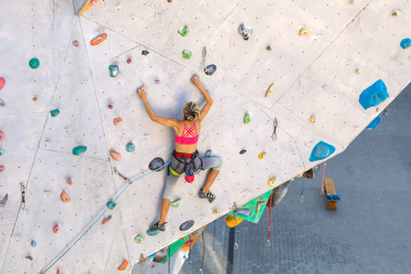A woman climbs a climbing wall, a climber is training on artificial terrain, rock climbing in the...