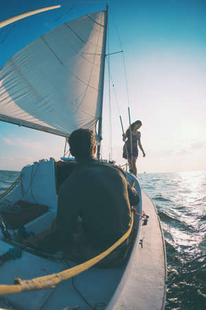 Romantic couple in love on sail boat traveling under sunlight on yacht, A man and a woman are on a sailing yacht.の写真素材