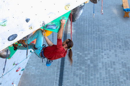A man climbs a climbing wall, a climber is training on artificial terrain, rock climbing in the...