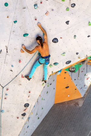 A man climbs a climbing wall, a climber is training on artificial terrain, rock climbing in the...