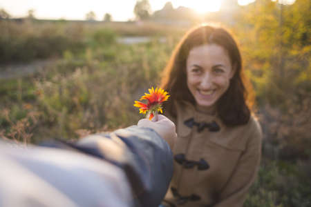 A child gives a flower to his mother, a boy walks with his mom, a woman sniffs a flower, a portrait of a smiling woman.の写真素材