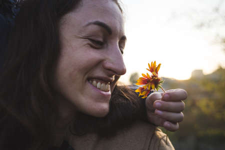 A child gives a flower to his mother, a boy walks with his mom, a woman sniffs a flower, a portrait of a smiling woman.の写真素材
