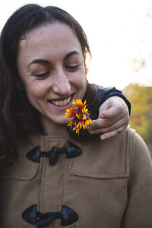 A child gives a flower to his mother, a boy walks with his mom, a woman sniffs a flower, a portrait of a smiling woman.の写真素材
