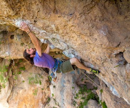 A strong man climbs a cliff, Climber overcomes a difficult climbing route on a natural terrain, Rock climbing in Turkey, Beautiful orange rock.の写真素材