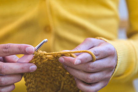 Woman crochets. Female hands close-up. The girl is engaged in needlework. A ball of yellow thread and a crochet hook.の写真素材
