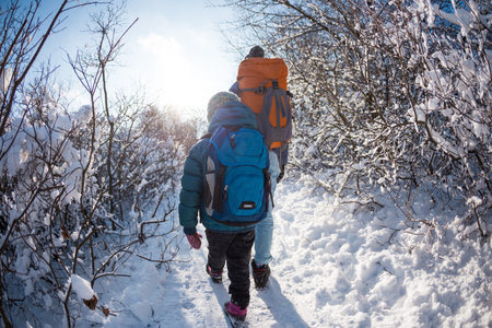 Woman with a child on a winter hike in the mountains, The boy travels with mother in the cold...