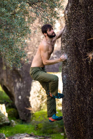 The climber climbs the stone. The athlete is engaged in bouldering. Rock climbing in nature. the concept of bouldering as a type of rock climbing and outdoor activities.の写真素材