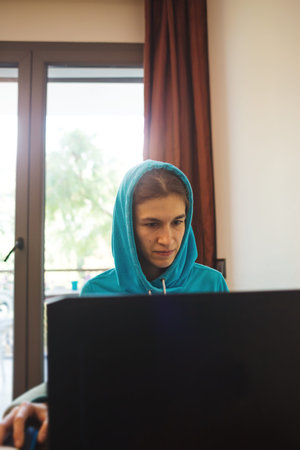 a young girl sits in an armchair and works with clients remotely, using the Internet and a computer....