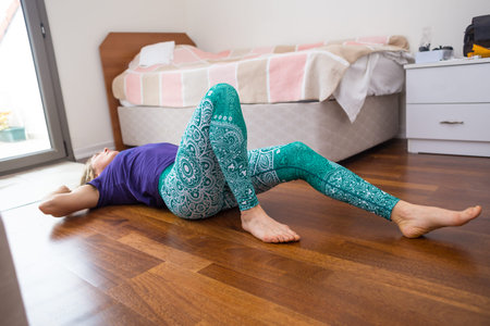 girl doing exercises on the floor of the room. yoga in the morning and during lockdown. female beauty and health.の写真素材