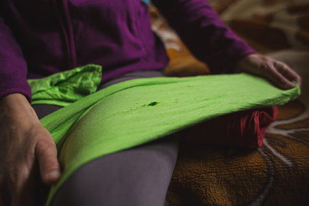 Woman holds torn clothes in her hands, Restoration of old clothes, Hole in the pants, Girl is preparing to protect the hole.の写真素材