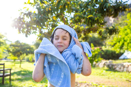 The child wipes with a towel after swimming in the pool. Wet boy wipes with a towel.の写真素材